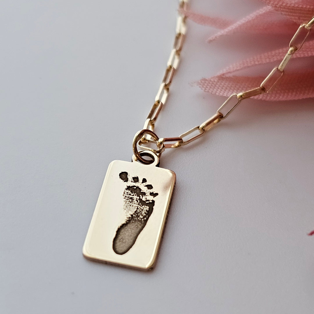 10k gold rectangle pendant with an engraved baby footprint